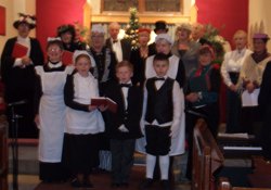 Members of Larne Concert Choir (back) took on the roles of  Lord and Lady Tickmacrevan with their guests. The staff were played by the Tickmacrevan Readers and three of the parish Young Members Group. At front, left to right; Blaze the scullery maid, Callum the butler and Jamie the footman. Next row, left to right, Dunlop the housemaid, Mrs Tinsley the housekeeper, Pullins the cook, Miss Penny the music teacher, Miss Julie the lady's maid and Miss Bessie the governess. Far right is Richard Barns, piano accompanist for the evening.